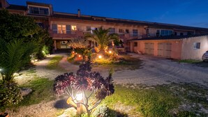 A residential building with a driveway, parked car, and illuminated garden lights.