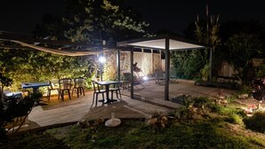 An outdoor patio area with a covered seating area, a table, and chairs.