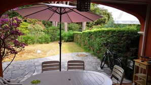 A patio with a round table and chairs, an umbrella, and a bicycle.