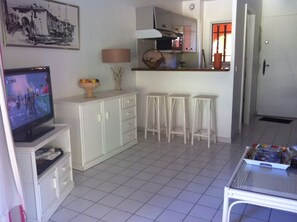 Un ambiente compatto con televisione, angolo cottura e posti a sedere.