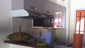 A compact kitchen with a microwave, a sink, and a small bar area with stools.