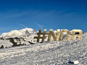 Paisaje nevado de montaña con un gran letrero '#NDR' en primer plano.