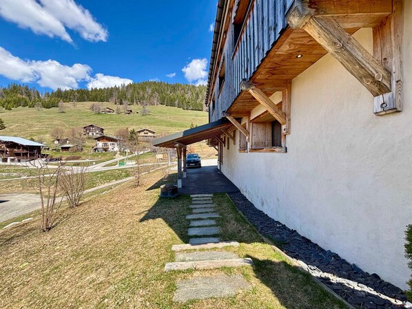 Un edificio con fachada de madera, un paseo techado y un camino de piedra que conduce a un vehículo.