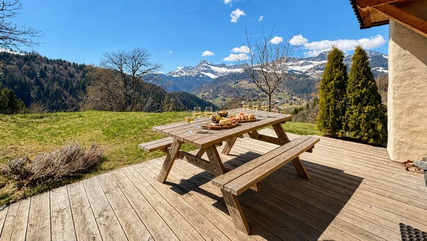 A wooden deck with a picnic table set up, overlooking a mountainous landscape. - Charming apartment with large terrace and parking (Notre-Dame-de-Bellecombe)