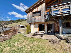 A two-story wooden cabin with a patio and a small tree. - Charming apartment with large terrace and parking (Notre-Dame-de-Bellecombe)