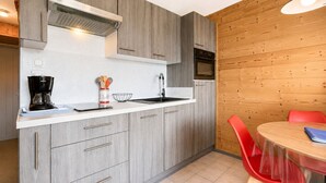 A modern kitchen with grey cabinetry, a built-in oven, and a coffee maker. - Ski-in studio with balcony views in Notre-Dame-de-Bellecombe (Notre-Dame-de-Bellecombe)
