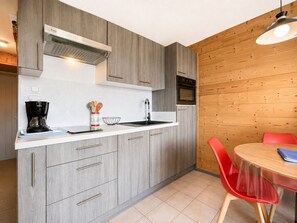 A modern kitchen with grey cabinetry, a built-in oven, and a coffee maker. - Ski-in studio with balcony views in Notre-Dame-de-Bellecombe (Notre-Dame-de-Bellecombe)
