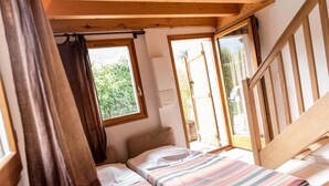 Ein kleiner, gemütlicher Raum mit einem Bett, einem Fenster und einer Treppe.