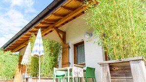 Ein Holzhaus mit überdachter Terrasse, Sitzgelegenheiten im Freien und einem Blumentopf.