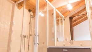 Ein Badezimmer mit Dusche, Spiegel und Waschtisch.