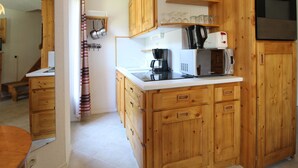 A compact kitchen with wooden cabinets, a microwave, a coffee maker, and a stove.