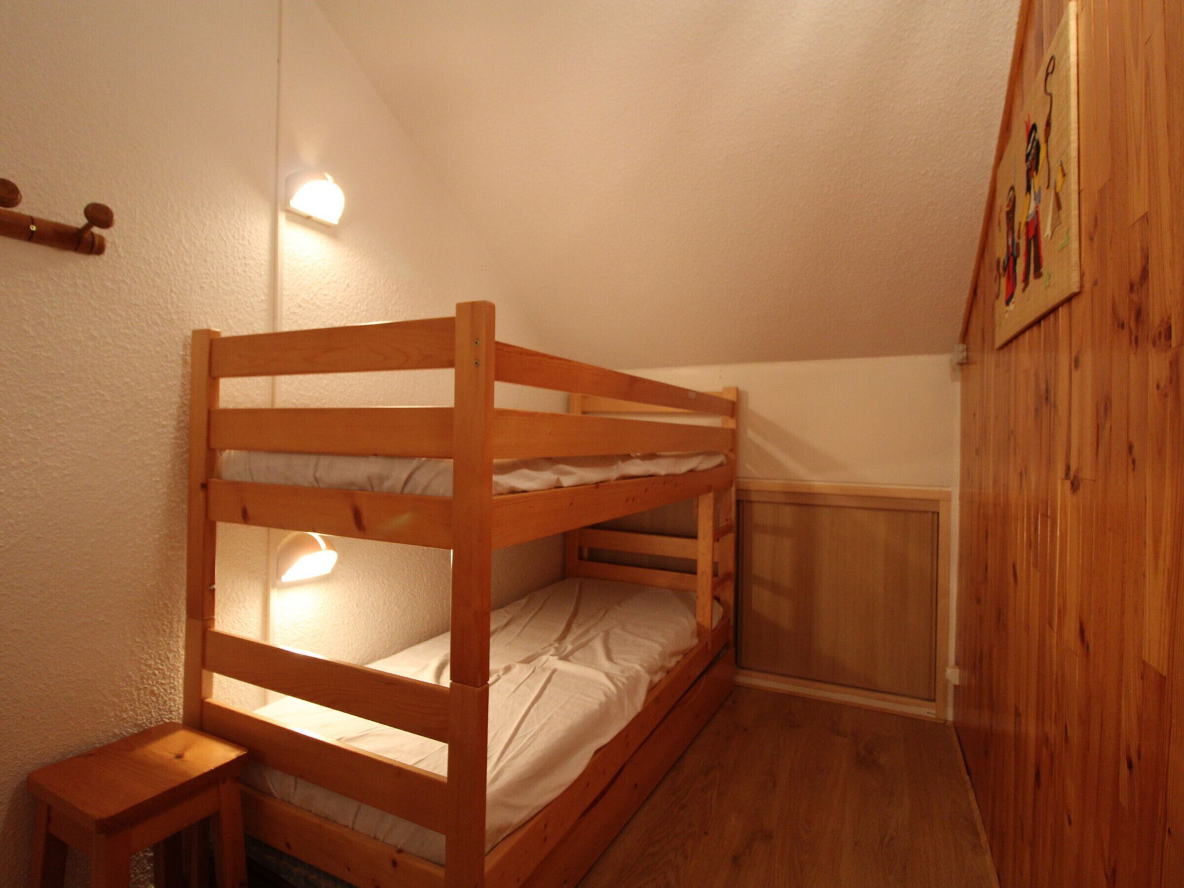 A bunk bed in a small room with a wooden floor and white walls.