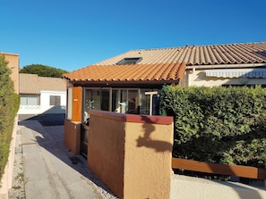Una propiedad residencial con techo de tejas, un patio cubierto y un seto cuidado.