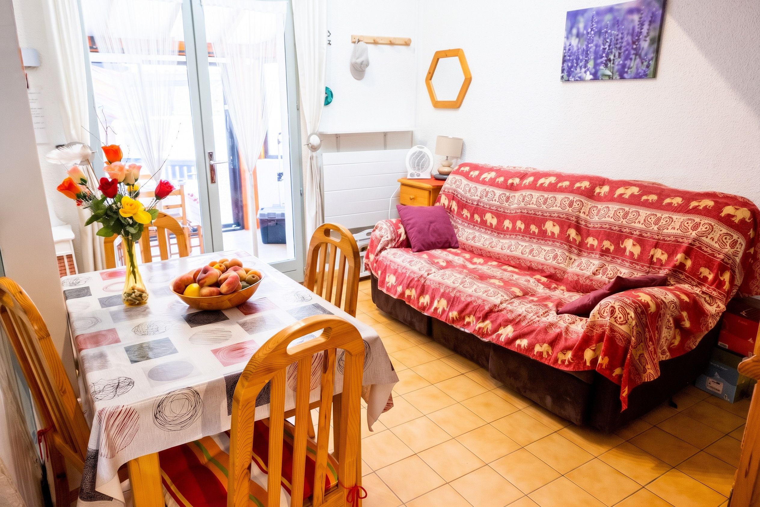 A cozy living area with a sofa, a dining table with chairs, and a vase of flowers.