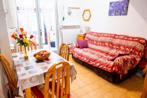 Un salon confortable avec un canapé, une table à manger et des chaises, ainsi qu’un vase rempli de fleurs.