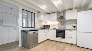 Une cuisine moderne avec des meubles blancs, un lave-vaisselle encastré, un four à micro-ondes, un four et un réfrigérateur.