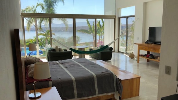 Un dormitorio con cama, hamaca, televisor y vista a un lago.