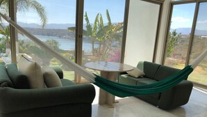 Una habitación con un sofá verde, una mesita redonda y una hamaca.
