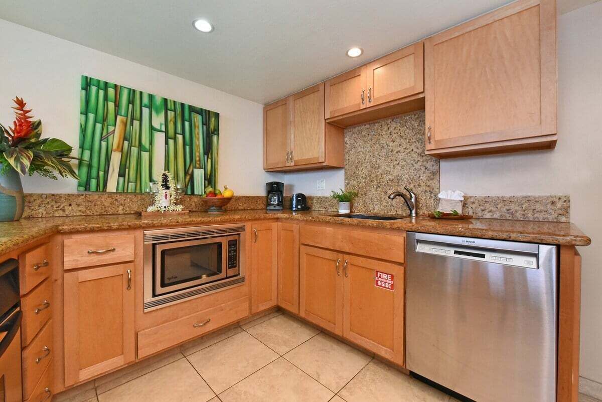 A kitchen with wooden cabinets, a microwave, a Bosch dishwasher, and a fire safety sign.