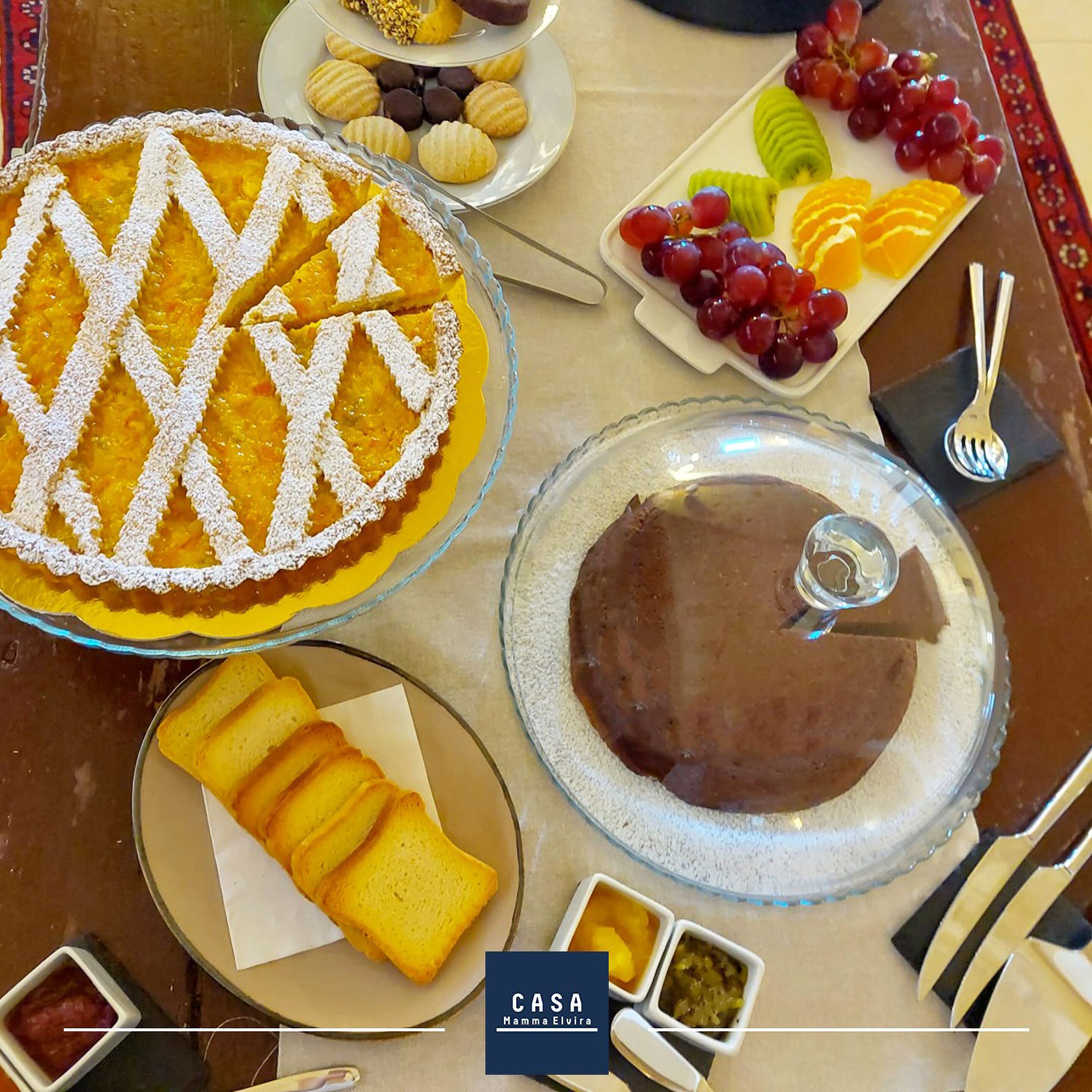 Una mesa servida con diversos postres, incluyendo tarta, pastel y fruta.