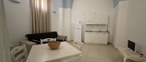 Un espacio habitable compacto con zona de comedor, kitchenette y sofá.