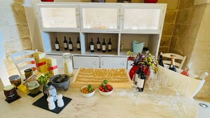 A kitchen with a marble countertop, wine bottles, a cheese board, and a red pot on the shelf. - Casa Mamma Elvira (Lecce)