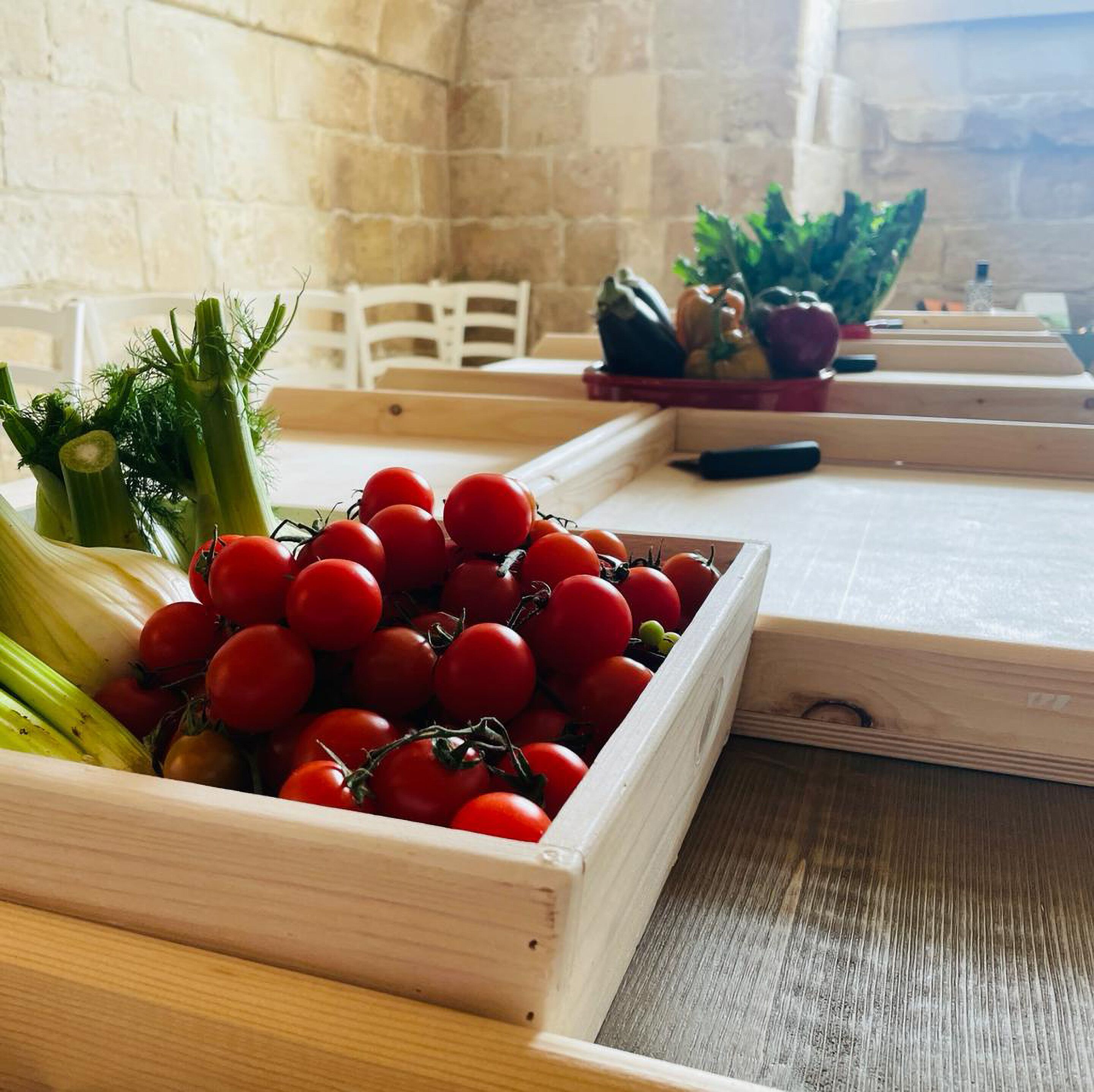 Une table en bois rustique sur laquelle repose une caisse en bois remplie de tomates fraîches et de céleri.