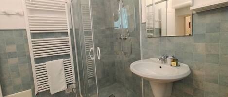 A bathroom with a glass-enclosed shower, a white sink, and a towel rack.