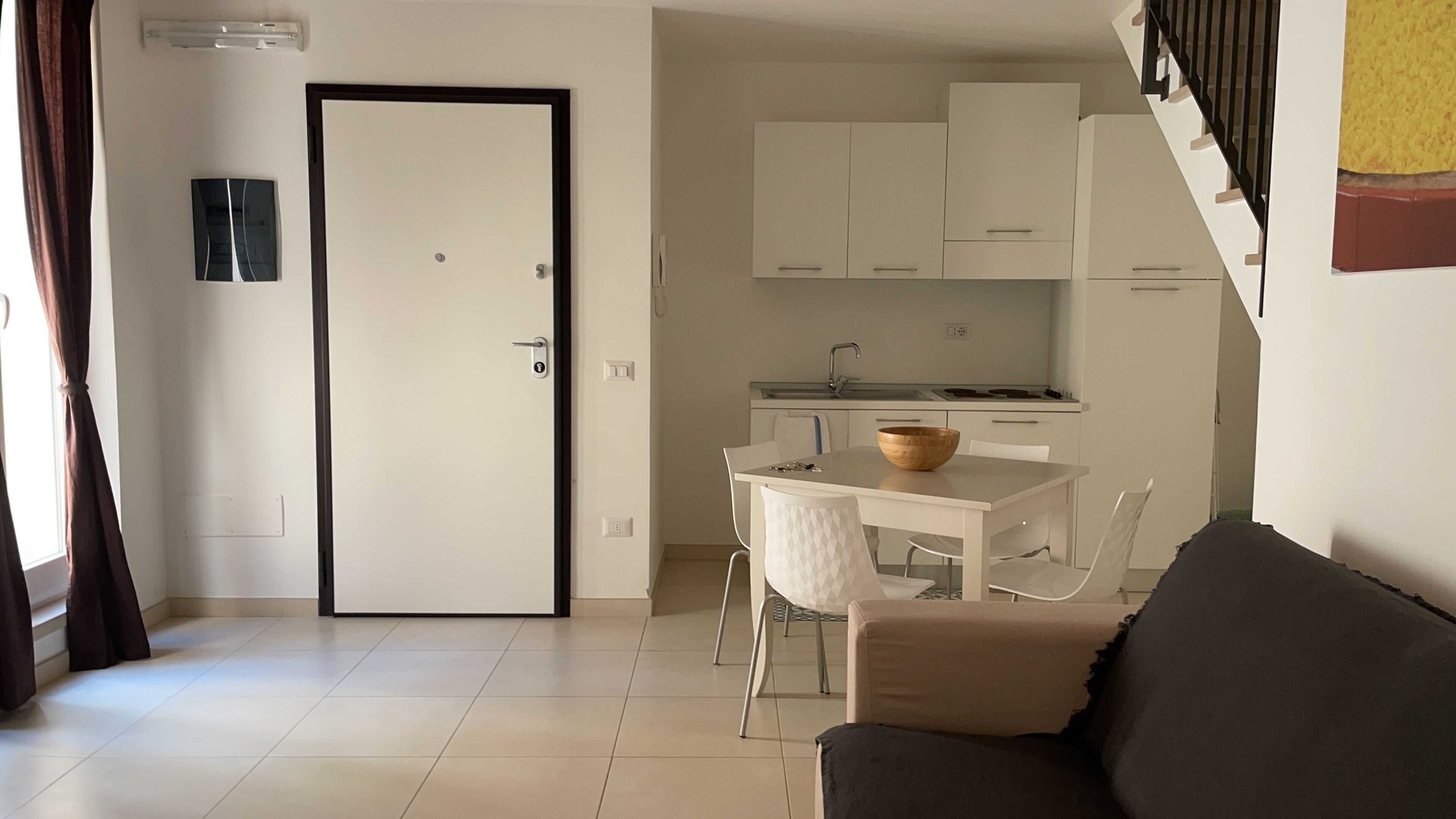 Um espaço de estar compacto com cozinha compacta, área de refeições e sofá.