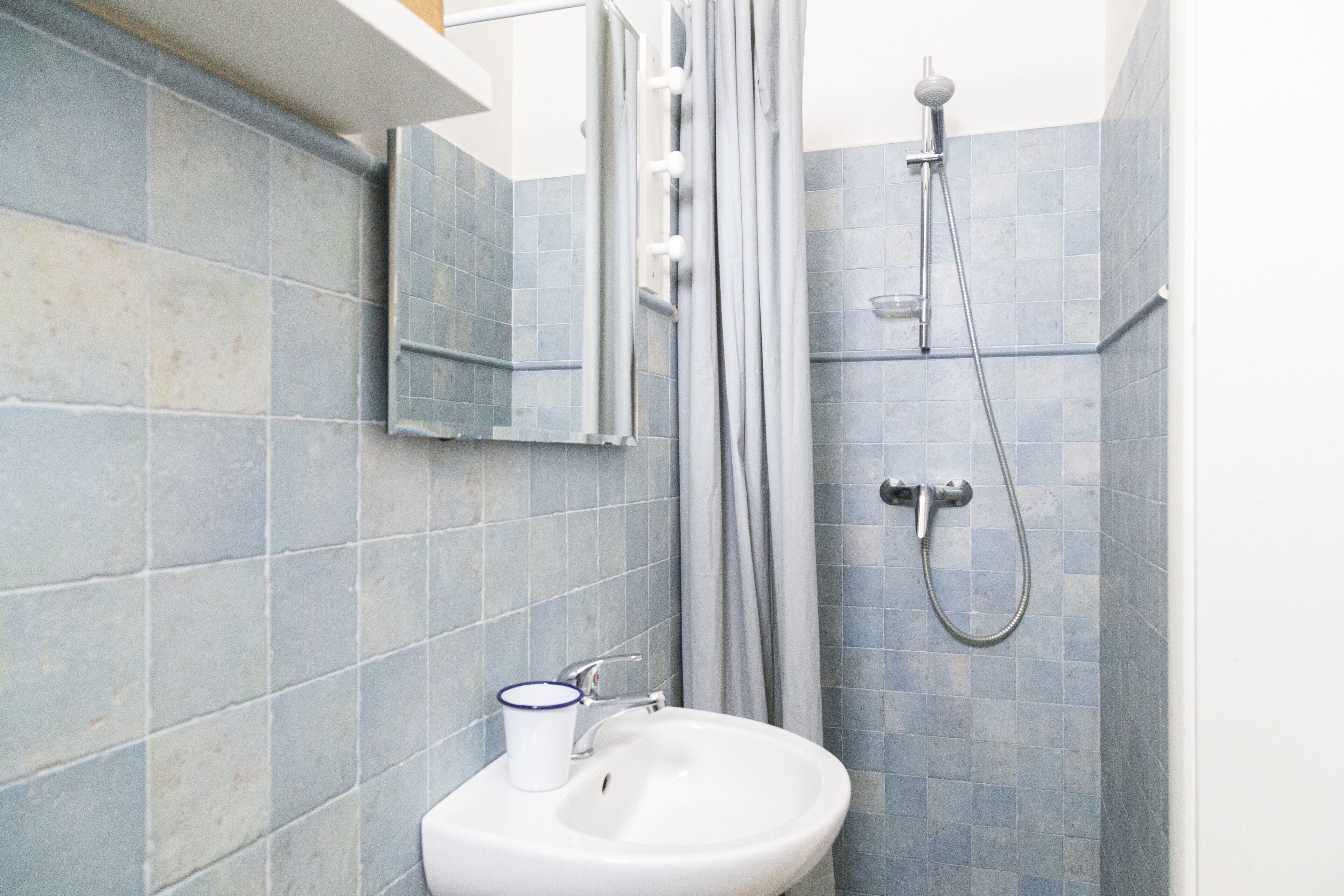 Un baño con lavamanos, espejo y ducha.