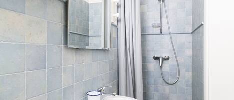Un baño con lavamanos, espejo y ducha.