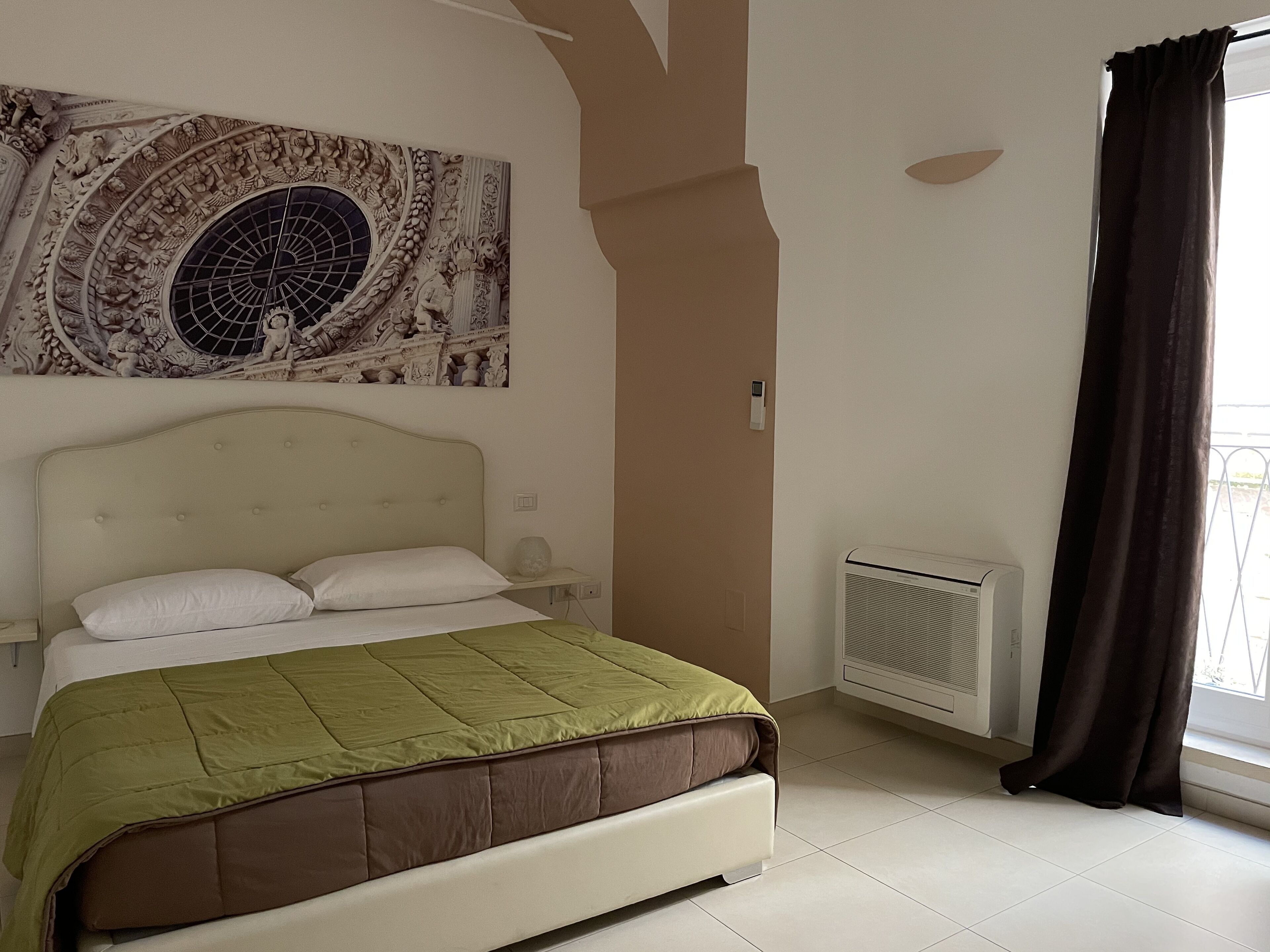 A bedroom with a bed, a wall-mounted air conditioner, and a window with curtains.