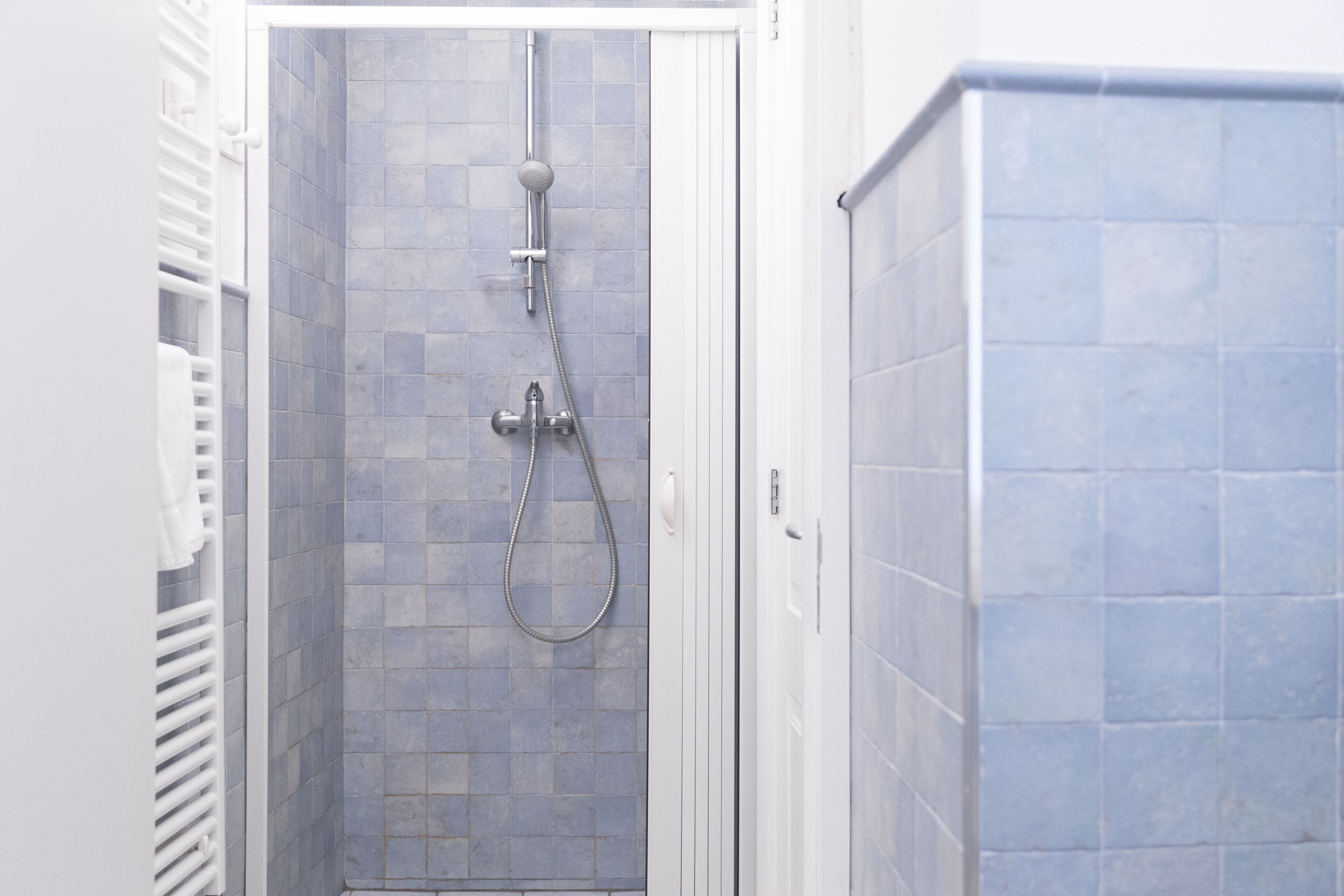 A walk-in shower with a tiled wall and a showerhead.