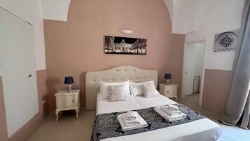 Une chambre à coucher avec un grand lit, deux tables de chevet, un tableau accroché au mur et un miroir décoratif.