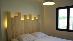A bedroom with a wooden headboard, a bed with white bedding, and a window with a view of greenery. - Cottage between sea and mountains with private pool (and heated) - View Pyrenees (Laà-Mondrans)