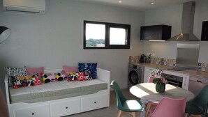 A compact living space with a sofa bed, a dining table with chairs, a washing machine, and a kitchen area. - Cottage between sea and mountains with private pool (and heated) - View Pyrenees (Laà-Mondrans)