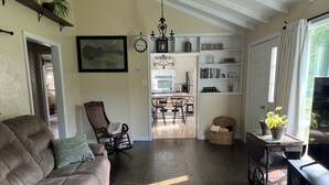 A spacious living room with a brown leather sofa, a wooden rocking chair, and a dining area with a chandelier. - HOT TUB,  BEACH 2 MINS, SEAFOOD, TRAILS, GOLF COURSES, DALVAY, DRIVE-IN THEATRE (York)