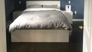A bedroom with a bed, a nightstand, a wall-mounted lamp, and a ceiling fan. - HOT TUB,  BEACH 2 MINS, SEAFOOD, TRAILS, GOLF COURSES, DALVAY, DRIVE-IN THEATRE (York)
