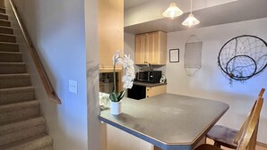Una cucina compatta con isola centrale, mobili in legno e forno a microonde.