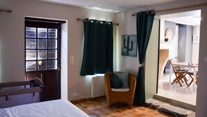 Une pièce comprenant un lit, une chaise, une fenêtre avec des rideaux, un radiateur et une porte.