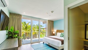 Een moderne hotelkamer met een groot bed, een televisie, een bureau met een plant en een balkon met uitzicht op palmbomen.