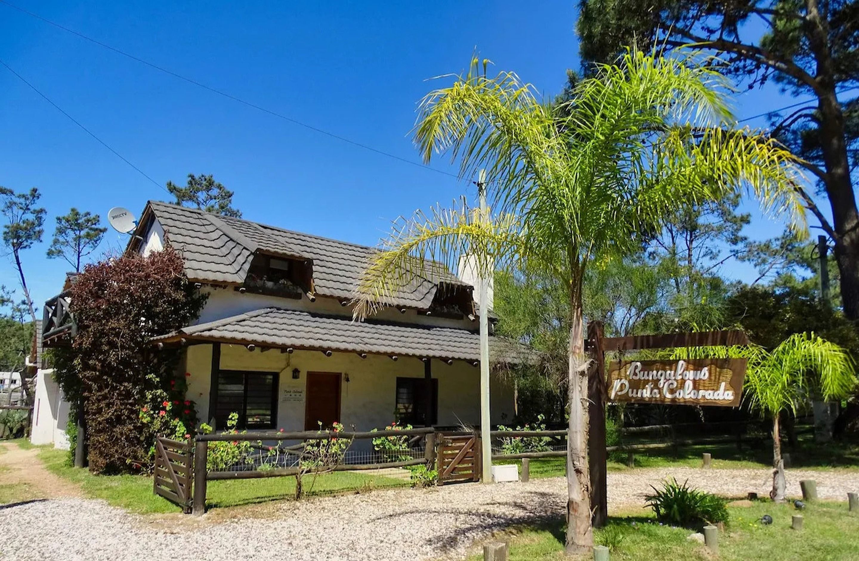 Un bungalow avec un toit en tuiles, une cour clôturée et une pancarte indiquant qu’il s’agit d’un bungalow situé à Punta Colorada.