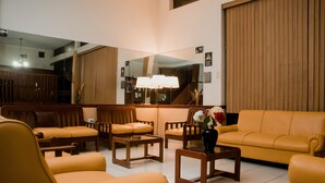 A modern living room with a large mirror, wooden furniture, and a sofa. - Hotel Amoretto (Trujillo)