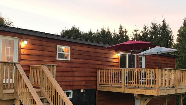 Een houten chalet met terras en trap.