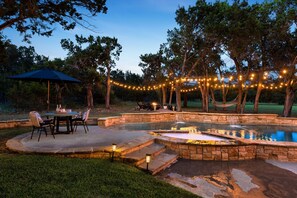 A backyard with a pool, stone steps, outdoor furniture, and string lights. - Private Studio | Pool + Spa + Tranquil Escape (Cedar Park)
