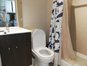 A bathroom with a toilet, sink, and dark wooden cabinet. - Apartment near the center. New, very welcoming. (Pucon)