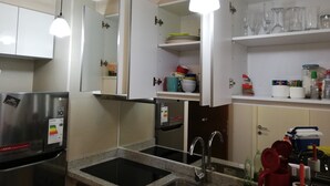 Une cuisine équipée d’un réfrigérateur en acier inoxydable, d’un plan de travail en granit, d’un évier et d’un éclairage au plafond.