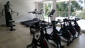 Une salle de sport équipée de vélos d’appartement, de tapis de course et d’appareils de musculation.