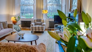 Una sala de estar con sofá, sillón, mesa de centro y televisor.