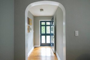 A hallway with a wooden floor, a white door with glass panels, and a light switch on the wall. - K9 Cottage @ Berwyn MainLine - No Pet Fees (Berwyn)